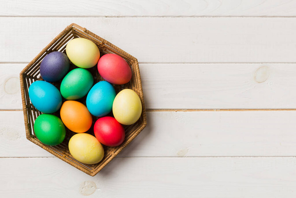 Многоцветные пасхальные яйца в плетеной корзине на цветном фоне. Пасхальные яйца пастельного цвета. праздничная концепция с местом для копирования. - Фото, изображение