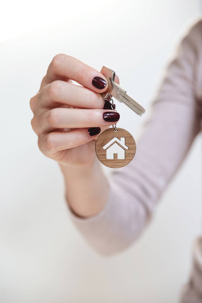 Real estate concept. Keys with a house shaped keychain in a womans hand. - Photo, Image