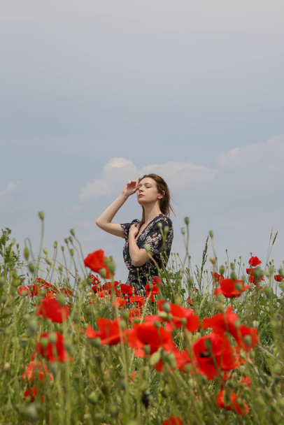 ケシ畑で腕を上げて花のドレスの若い女性。気楽なライフスタイルをリラックス。自由の概念. - 写真・画像