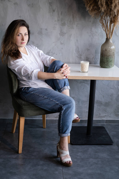 beautiful brunette woman girl in white blouse and jeans in loft cafe interior. coffee break. happy worker. - Photo, Image