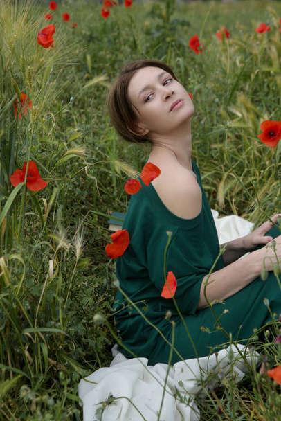 Young woman in poppy field . Relaxing carefree lifestyle. Daydreaming in summer meadow.  - Photo, Image