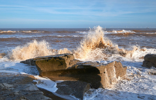 Хвилі розбиваються над бетонними блоками на пляжі
 - Фото, зображення
