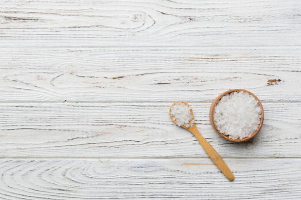 A wooden bowl of salt crystals on a wooden background. Salt in rustic bowls, top view with copy space. - Foto, immagini