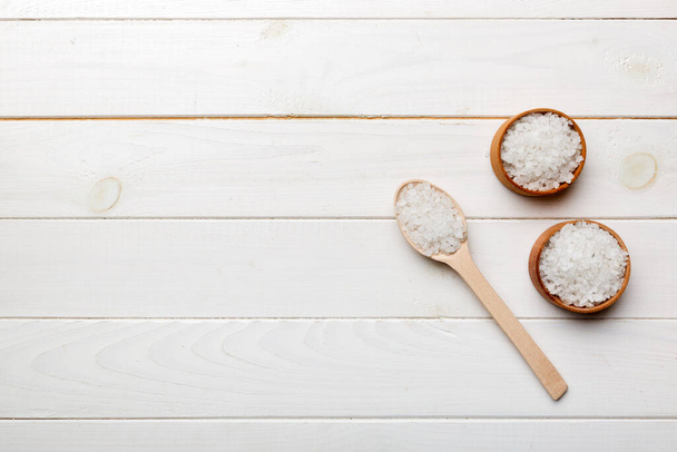 A wooden bowl of salt crystals on a wooden background. Salt in rustic bowls, top view with copy space. - Foto, imagen