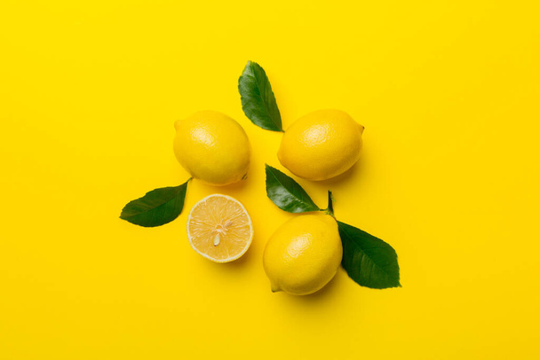 緑の葉を持つ多くの新鮮な熟したレモンの色の背景、トップビュー、テキストのためのスペース. - 写真・画像