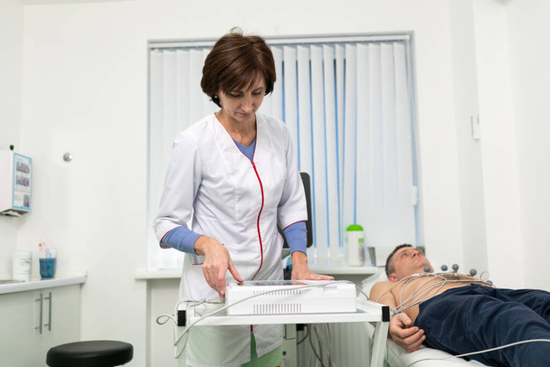 Medical equipment for electrocardiogram. Doctors doing ECG test on male patient. Diagnostic heart disease heart attack, tachycardia. Electrocardiography procedure. Cardiologist doing check-up test. - Φωτογραφία, εικόνα
