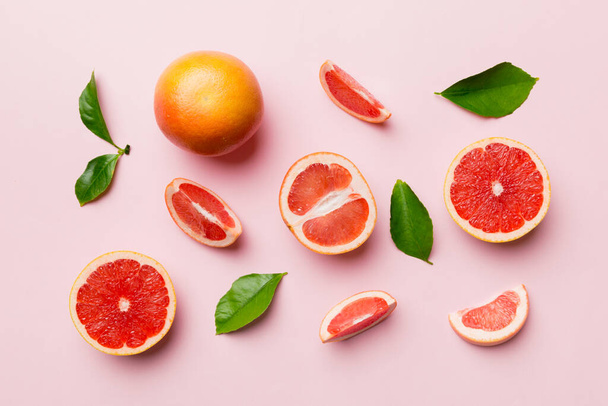 ジューシーなグレープフルーツのスライスを色の背景に新鮮なフルーツグレープフルーツ。最上階だ。コピースペース。創造的な夏のコンセプト。コピースペースと最小限のフラットレイアウトで柑橘類の半分. - 写真・画像