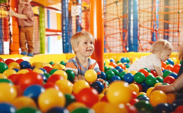 Niños felices jugando en Ball Pool. Niños divirtiéndose en la piscina de bolas del parque infantil en el centro de atracciones  - Foto, imagen