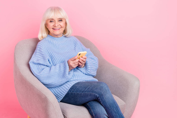 Portrait of attractive cheery grey-haired woman using gadget device blogging post app isolated over pink pastel color background - Foto, immagini