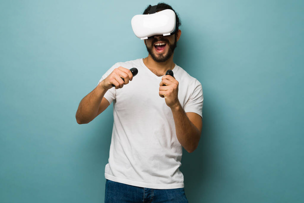 Szczęśliwy Hiszpan noszący zestaw słuchawkowy VR i grający w zabawną grę wideo wirtualnej rzeczywistości  - Zdjęcie, obraz