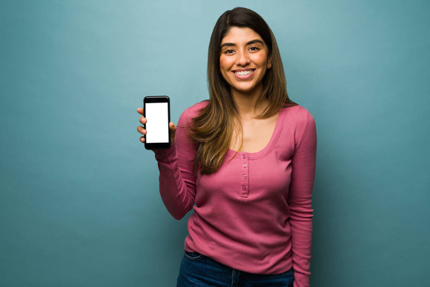 Portrait d'une magnifique jeune femme montrant son écran de smartphone et des messages texte - Photo, image