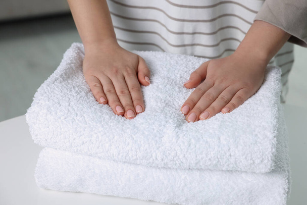 Woman touching soft white towel indoors, closeup - Zdjęcie, obraz