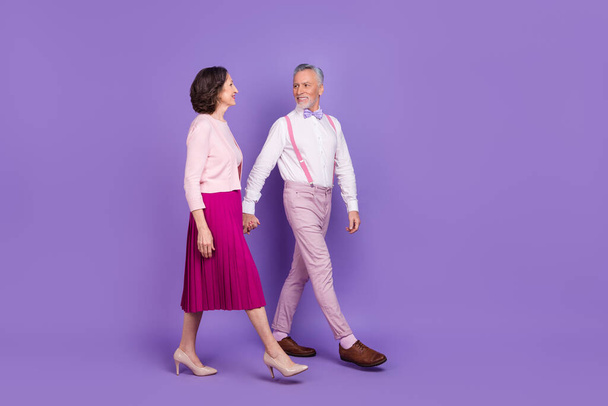 Full length profile photo of two elegant lovely partners walking hold hands isolated on purple color background - Foto, Imagem