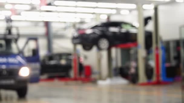 Raised car in professional service repair process, unfocused background. - Footage, Video