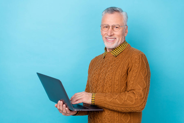 Photo of marketer stylish trendy middle aged man hold netbook chatting isolated blue color background - Foto, afbeelding