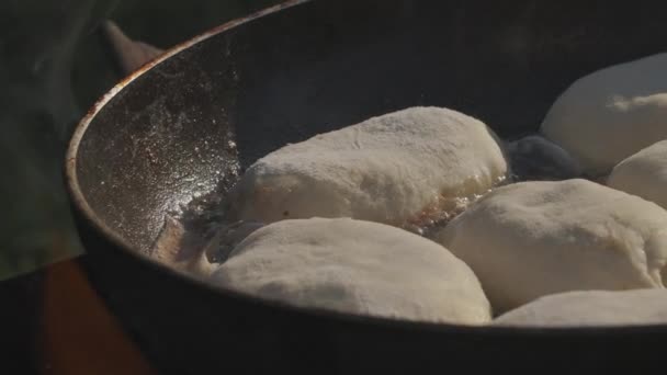 Taartjes in een pan. Creatief. Het deeg wordt gebakken in een hete pan. De olie kookt. Eten bakken in de natuur op een open vuur - Video