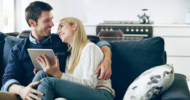 Mutluluk böyle bir şey işte. Sevecen genç bir çiftin evdeki kanepelerinde otururken dijital tablet kullanırken çekilmiş görüntüleri.. - Fotoğraf, Görsel