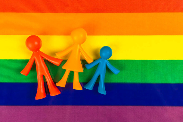 LGBT vlajka hrdosti s rodinnými figurkami. Gay a lesbičky homosexuální láska pozadí fotografie - Fotografie, Obrázek