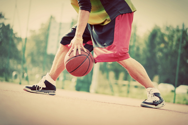 Mann auf Basketballfeld dribbelt mit Ball. - Foto, Bild