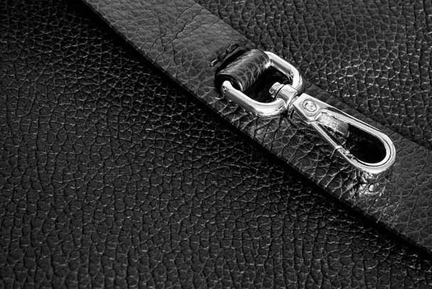 Goldkarabiner aus Metall mit einem Ring am Riemen einer schwarzen Tasche - Foto, Bild