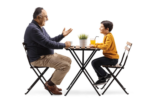 Grandfather sitting at a cafe table and talking to a grandson isolated on white background - Foto, immagini