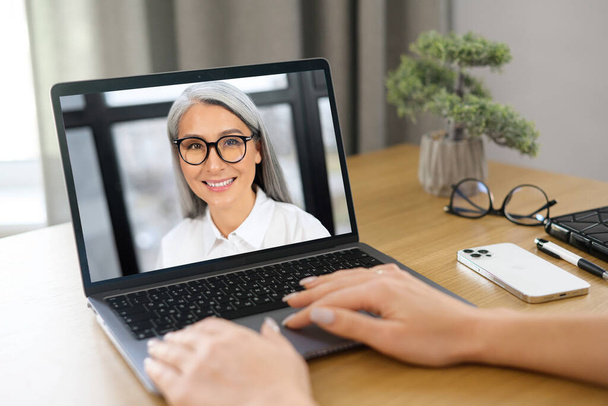Video call to female employee or friend. Two woman is talking online via video connection on laptop indoor, they are greeting each other - Photo, Image