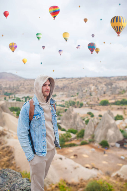 Счастливый молодой человек смотрит воздушные шары в Каппадокии, Турция - Фото, изображение