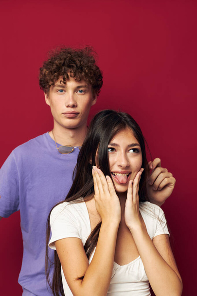 a guy stands behind a girl and holds her hair red background - Foto, Imagem