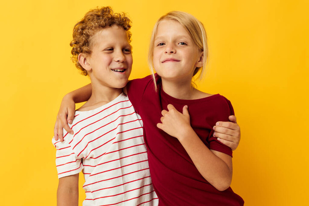 obraz pozytywnego chłopca i dziewczyny stojących obok siebie stwarzających emocje z dzieciństwa żółte tło - Zdjęcie, obraz