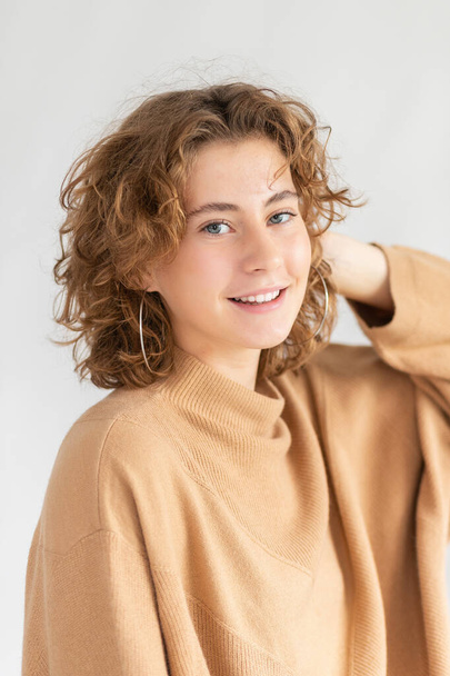 Woman with curly beautiful hair on gray background. Girl with beauty a pleasant smile. Short wavy hairstyle - Zdjęcie, obraz