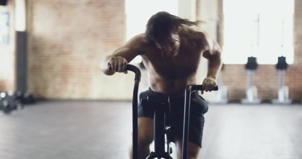 Он старается изо всех сил. 4k видео мускулистого молодого человека, тренирующегося на велотренажере в спортзале. - Кадры, видео