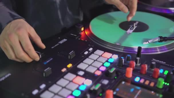 DJ draaitafel bij disco. Kunst. Close-up van DJ 's hand op mixer. Een gloeiend muziekpaneel op een feestje. Muzikanten werken in nachtclub - Video