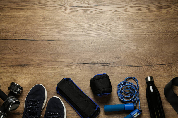 Blue weighting agents and sport equipment on wooden table, flat lay. Space for text - Fotoğraf, Görsel