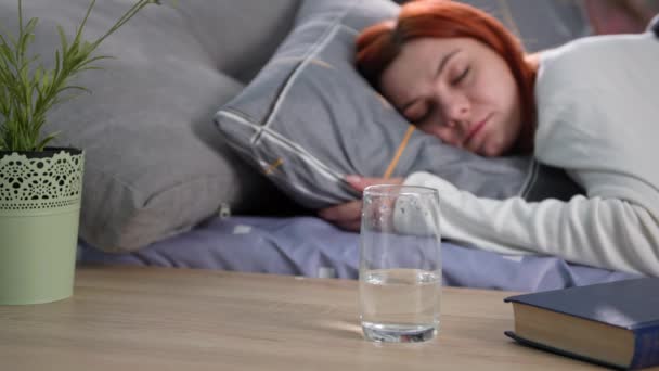 morning rituals, a young female drinks clean healthy water in a glass after waking up from sleep while lying in bed, close-up - Footage, Video
