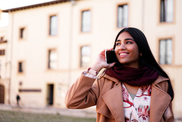 retrato de cerca de la joven india hablando por teléfono al aire libre - Foto, Imagen
