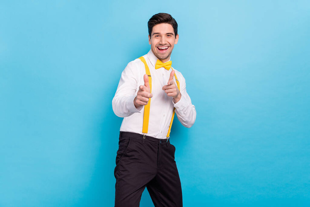 Photo of adorable excited guy dressed white shirt yellow bowtie pointing fingers you isolated blue color background - Foto, Imagem