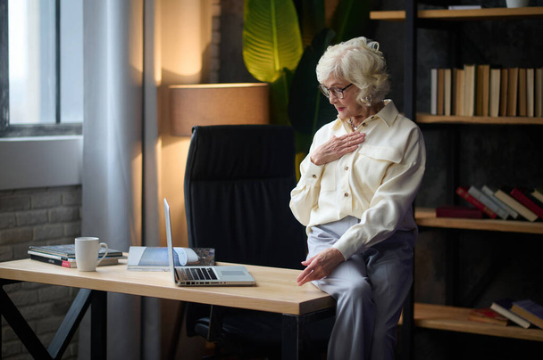 Woman speaking confidently looking at laptop sitting on desk - Zdjęcie, obraz