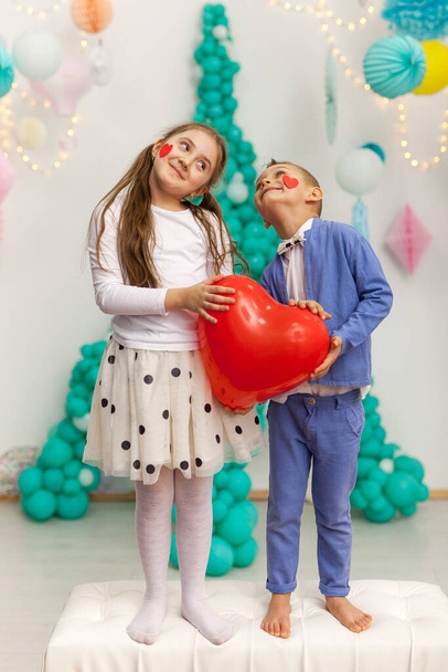 Linda pareja de niños con globo de corazón rojo. Día de San Valentín y concepto de amor, toma de estudio - Foto, Imagen