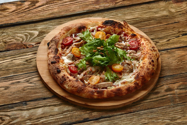 Pizza Caesar. Pizza met kip, tomaat, kaas en sla op houten plank. Bovenaanzicht. Vrije ruimte voor uw tekst. Leveringsvoedsel - Foto, afbeelding