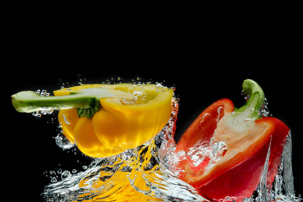 Splattered colored bell peppers splashed on a black background with a cut-out background. - Photo, Image