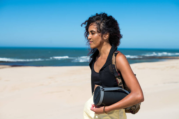Nainen kävelemässä bluetooth-kaiuttimella rannikolla - Valokuva, kuva