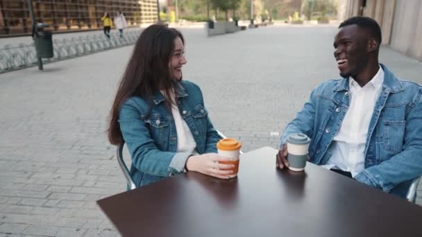 Cheerful multiethnic couple drinking coffee in city - Footage, Video