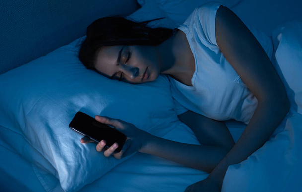 Tired woman falling asleep after browsing smartphone - Foto, imagen