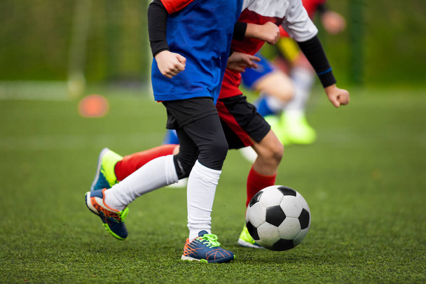 Детский футбольный мяч на травяном поле. Двое школьников бегут на дуэли и соревнуются в футболе - Фото, изображение