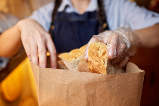 female hands cutting wheaten bread on the wooden board, selective focus. - 写真・画像