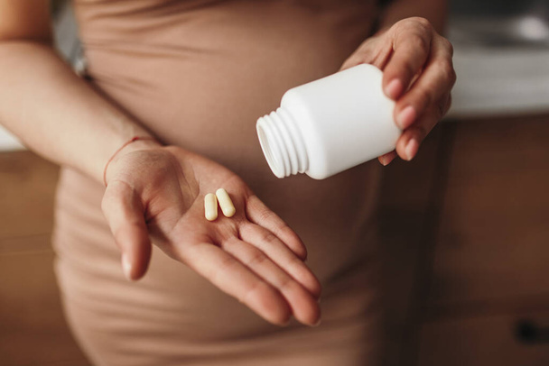 Crop pregnant lady drinking vitamin tablets - Photo, image