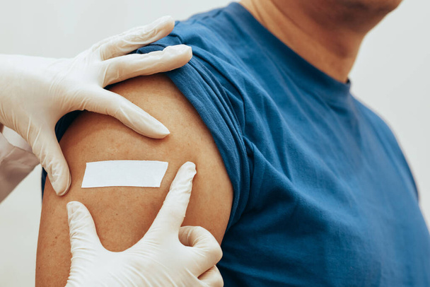 Nurse sticks patch on man after vaccination. The concept of worldwide vaccination against Coronovirus Omicron - Φωτογραφία, εικόνα