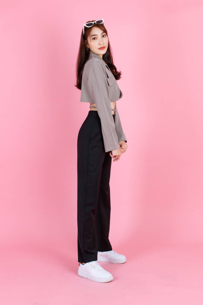 Portré stúdió lövés ázsiai fiatal városi trendi női hipster tinédzser divat modell alkalmi növényi top utca visel kabát gazdaság napszemüveg a fejen álló nézd meg a kamera rózsaszín háttér. - Fotó, kép