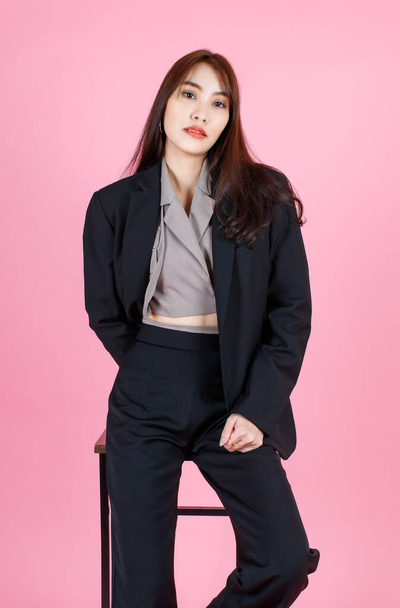 Portrait Studioaufnahme von asiatischen schönen städtischen trendigen modernen langen Haaren weibliche Hipster Teenager-Modell in lässigem schwarzen Anzug mit bauchfreiem Hemd im Stehen Blick in die Kamera auf rosa Hintergrund. - Foto, Bild