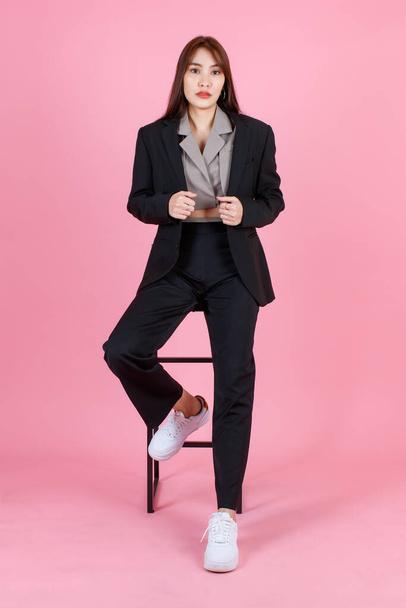 Portrait studio shot of Asian beautiful urban trendy modern fashionable long hair female hipster teenager model in casual black suit with crop top shirt standing look at camera on pink background. - Fotografie, Obrázek